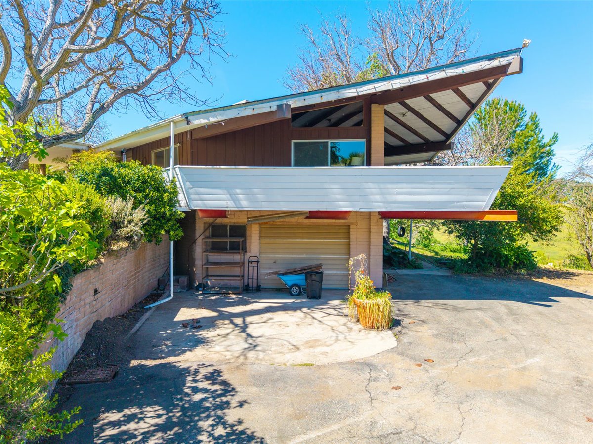 Exterior of the Atascadero family home with a dramatic angled roof, wood board siding and a brick retaining wall